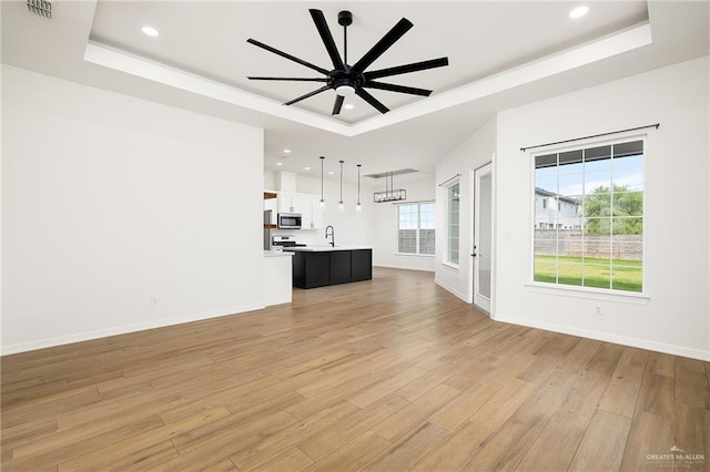 3515 Elevation Dr, Edinburg, TX 78542 - unfurnished living room with a tray ceiling and light wood-style floors