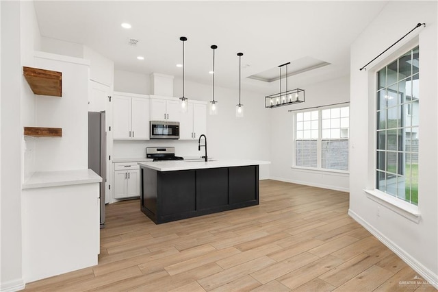 3515 Elevation Dr, Edinburg, TX 78542 - kitchen with white cabinets, a raised ceiling, a sink, light wood-type flooring, and appliances with stainless steel finishes