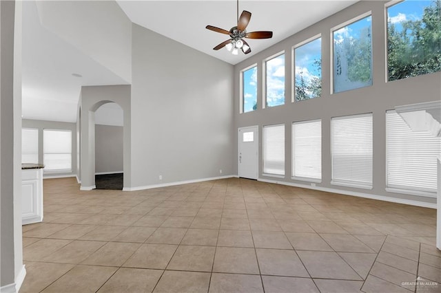 tiled spare room with ceiling fan and high vaulted ceiling