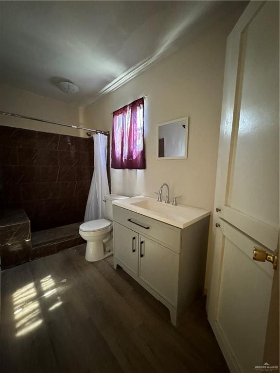 bathroom with hardwood / wood-style floors, vanity, toilet, and walk in shower