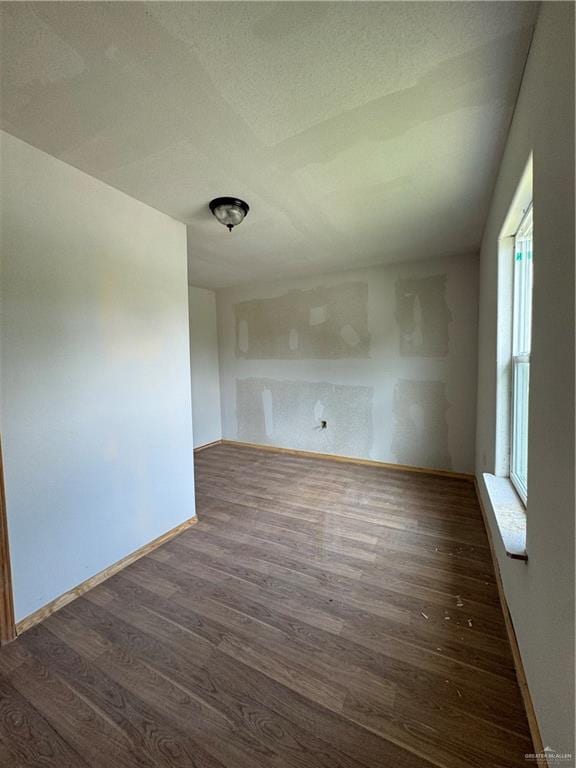 spare room featuring a textured ceiling, dark hardwood / wood-style flooring, and a healthy amount of sunlight