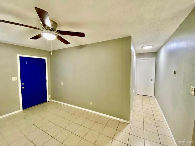 spare room featuring a textured ceiling, ceiling fan, baseboards, and light tile patterned flooring