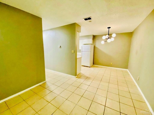 empty room with baseboards, light tile patterned floors, and a notable chandelier