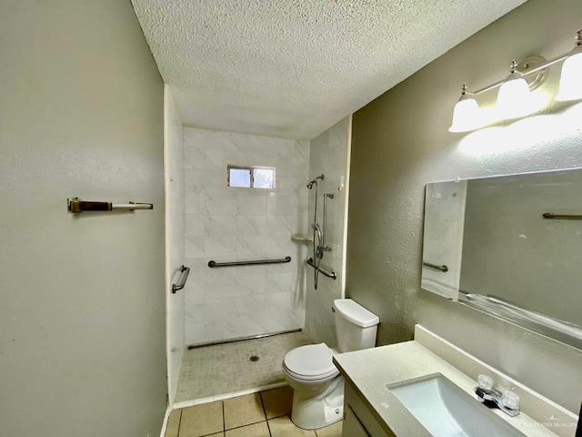 bathroom with a textured ceiling, tile patterned floors, vanity, toilet, and tiled shower