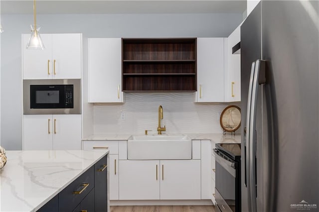 kitchen featuring white cabinetry, sink, hanging light fixtures, stainless steel appliances, and light stone counters