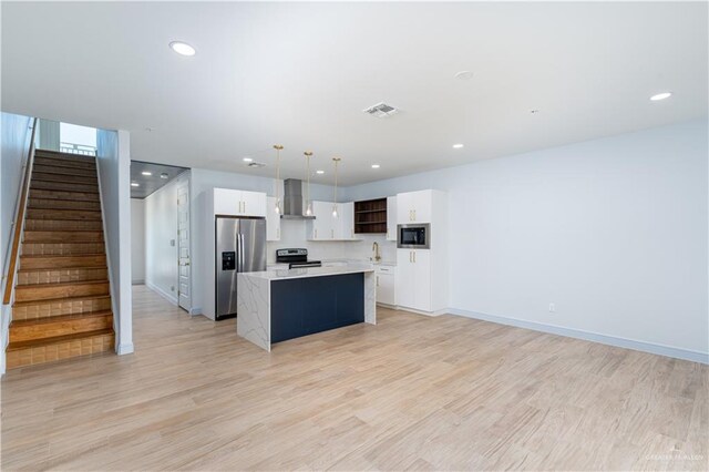 kitchen with stainless steel appliances, a kitchen island, pendant lighting, light hardwood / wood-style flooring, and white cabinetry