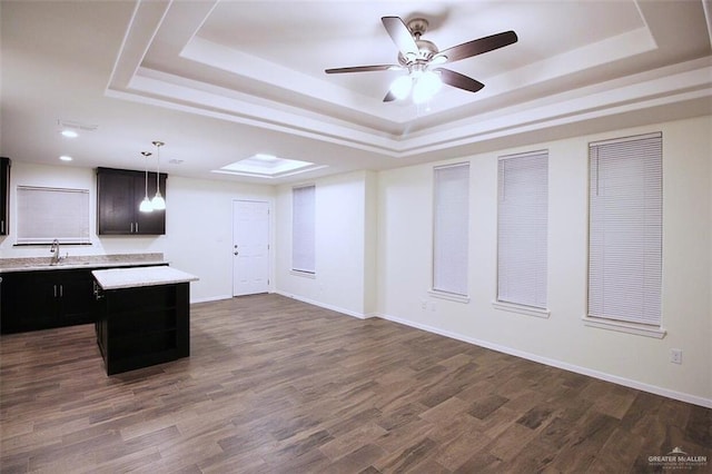 kitchen featuring a raised ceiling, dark wood-type flooring, a center island, and hanging light fixtures