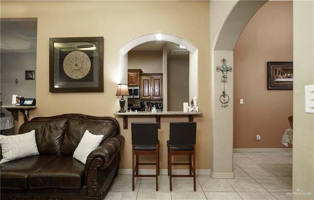 1110 E 8th St N, San Juan, TX 78589 - bar area featuring stainless steel microwave, arched walkways, light tile patterned flooring, and baseboards