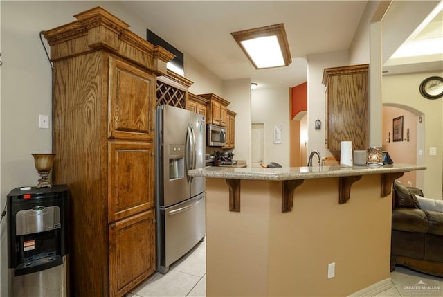 1110 E 8th St N, San Juan, TX 78589 - kitchen featuring stainless steel appliances, a breakfast bar, arched walkways, light tile patterned floors, and a peninsula
