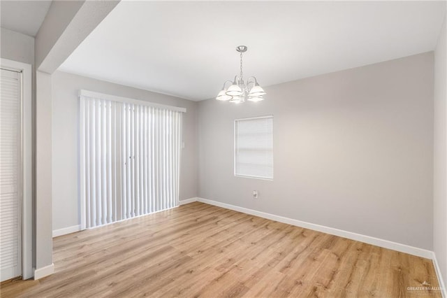 spare room featuring an inviting chandelier and light hardwood / wood-style flooring