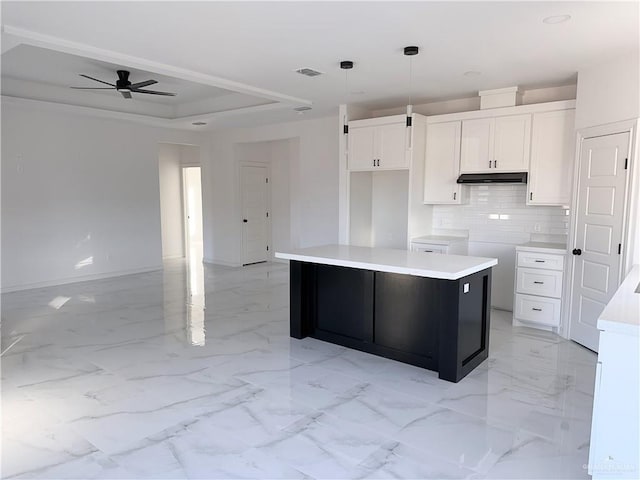 kitchen with white cabinetry, tasteful backsplash, a tray ceiling, a kitchen island, and pendant lighting