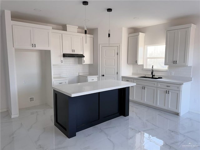 kitchen with sink, tasteful backsplash, a kitchen island, pendant lighting, and white cabinets