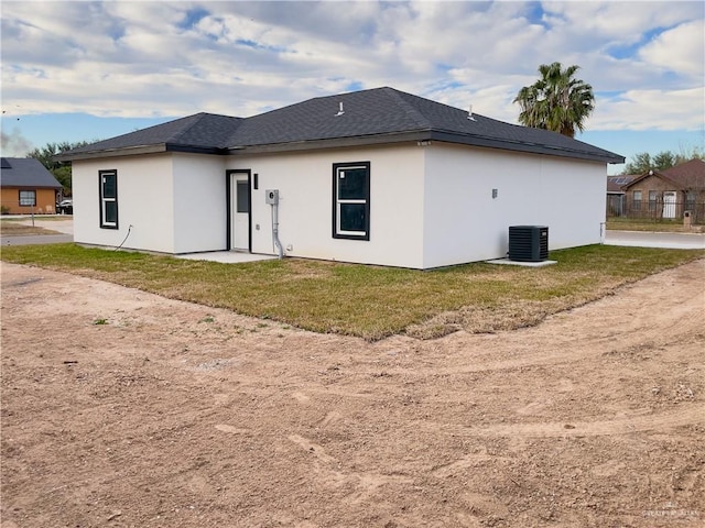 rear view of property featuring cooling unit and a yard