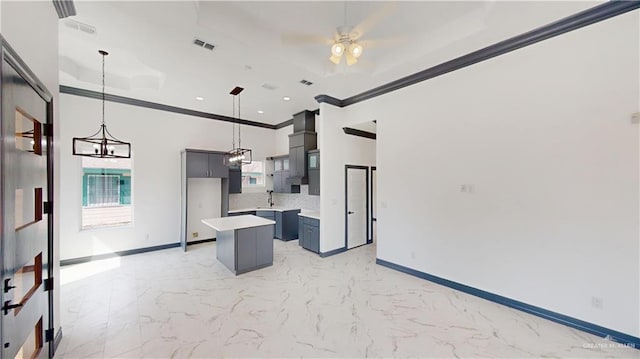 513 E Hawk Ave, Pharr, TX 78577 - kitchen featuring a center island, crown molding, light countertops, a ceiling fan, and light marble finish flooring