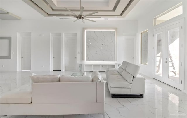 unfurnished living room featuring marble finish floor, a ceiling fan, a tray ceiling, coffered ceiling, and french doors