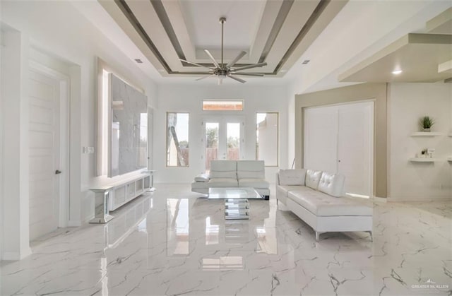 unfurnished living room featuring french doors, a raised ceiling, marble finish floor, and ceiling fan