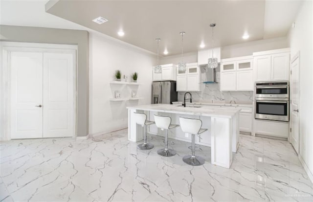 kitchen with marble finish floor, tasteful backsplash, white cabinetry, stainless steel appliances, and a breakfast bar area