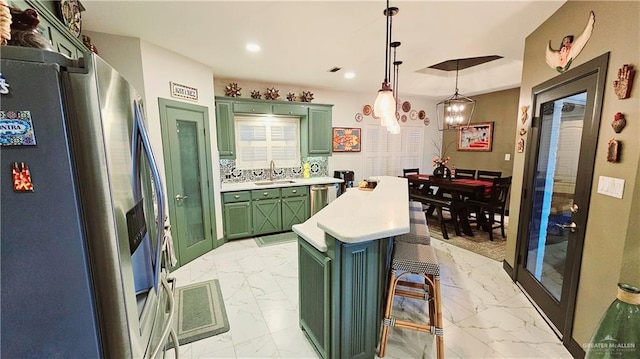 kitchen featuring sink, a breakfast bar area, decorative light fixtures, stainless steel fridge with ice dispenser, and a kitchen island