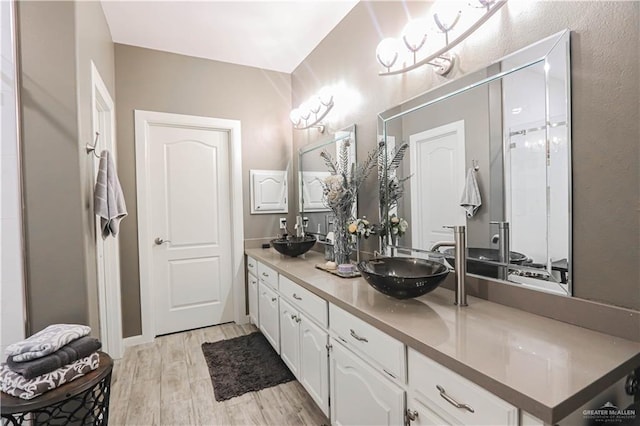 bathroom featuring double vanity, wood finished floors, and a sink