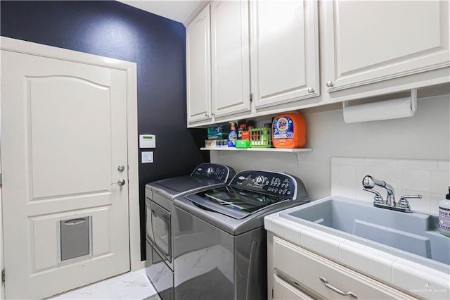 clothes washing area featuring marble finish floor, a sink, cabinet space, and washer and dryer