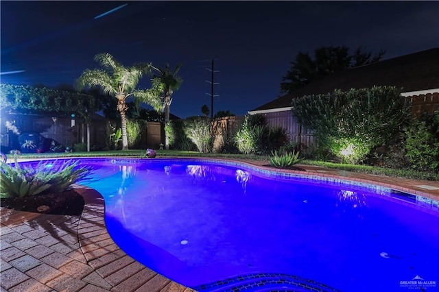 pool at twilight with a patio area, a fenced backyard, and a fenced in pool