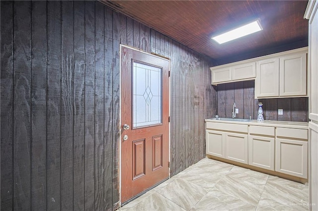 kitchen with light countertops, wooden ceiling, a sink, and white cabinets