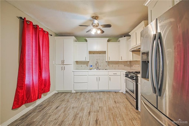 kitchen with stainless steel appliances, light countertops, light wood-type flooring, under cabinet range hood, and a sink