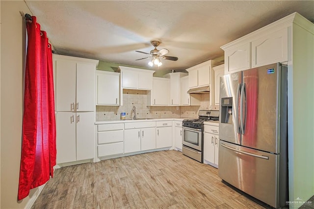 kitchen with sink, white cabinetry, tasteful backsplash, light wood-type flooring, and stainless steel appliances