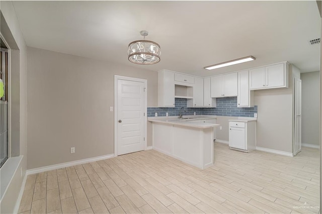 kitchen featuring pendant lighting, white cabinetry, light hardwood / wood-style floors, decorative backsplash, and kitchen peninsula