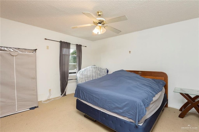 bedroom with ceiling fan, light colored carpet, and a textured ceiling