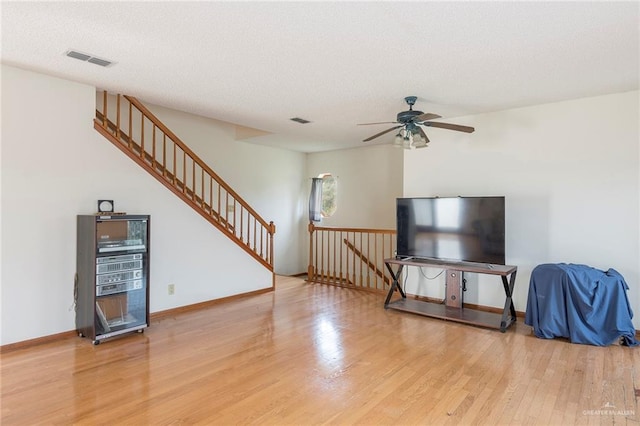 living room with hardwood / wood-style flooring, ceiling fan, and a textured ceiling