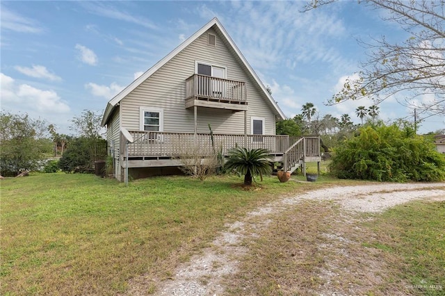 back of house with a balcony, a deck, and a lawn