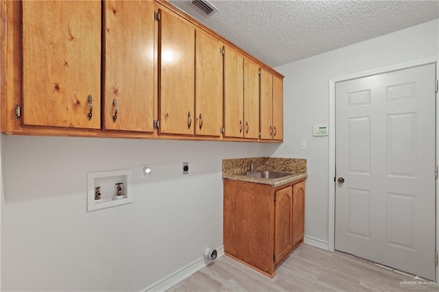 laundry area featuring cabinet space, washer hookup, light wood finished floors, hookup for an electric dryer, and visible vents