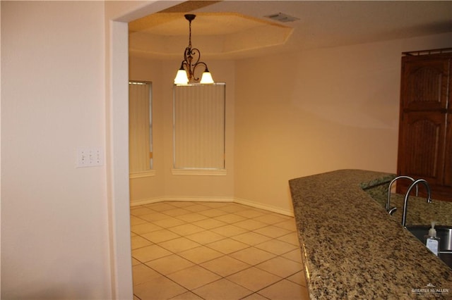 dining room featuring a tray ceiling, sink, light tile patterned floors, and a chandelier