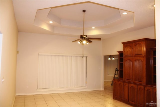 interior space featuring ceiling fan, light tile patterned floors, and a tray ceiling