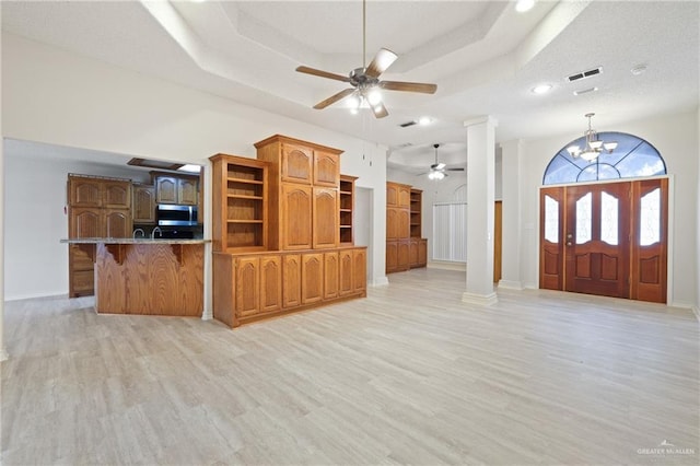 entrance foyer with ceiling fan with notable chandelier, light wood finished floors, ornate columns, a tray ceiling, and recessed lighting