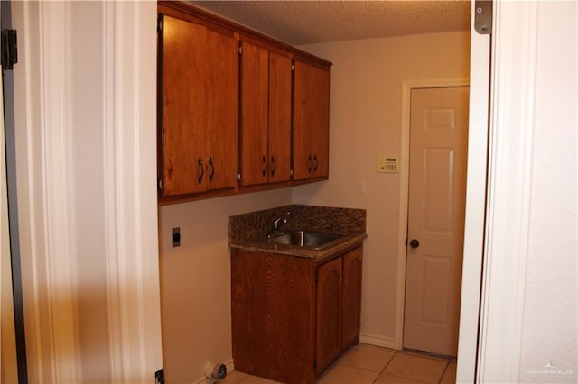 kitchen with sink, light tile patterned flooring, and a textured ceiling