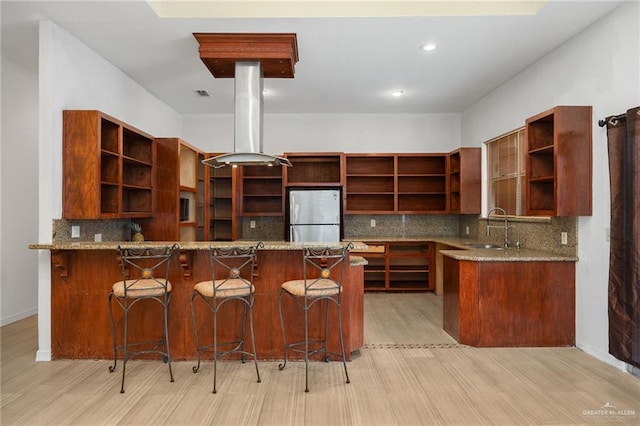 kitchen with light hardwood / wood-style flooring, island range hood, stainless steel refrigerator, and sink