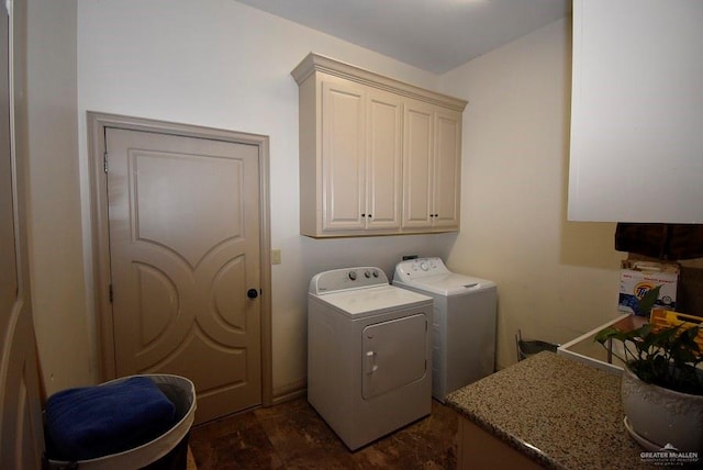 clothes washing area featuring cabinets and separate washer and dryer