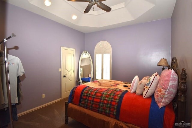 carpeted bedroom with a tray ceiling and ceiling fan