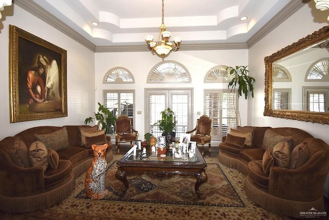 living room featuring ornamental molding, a tray ceiling, and an inviting chandelier