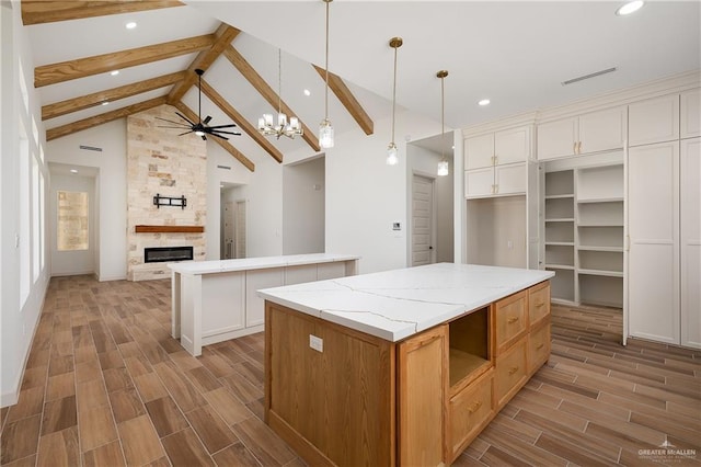 8100 Coyote Dr, Mission, TX 78574 - kitchen featuring a center island, beamed ceiling, wood finish floors, a stone fireplace, and recessed lighting