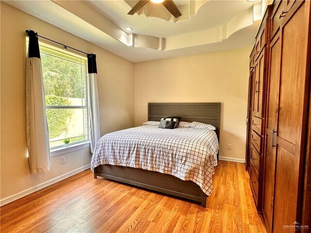 2401 S Gardenia St, Pharr, TX 78577 - bedroom with light wood finished floors, baseboards, ceiling fan, and a tray ceiling