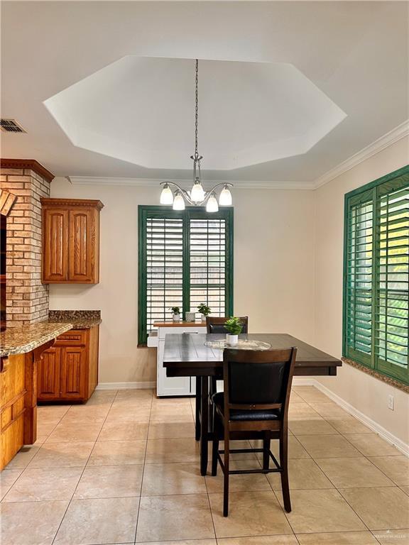 2401 S Gardenia St, Pharr, TX 78577 - dining space featuring healthy amount of natural light, a raised ceiling, light tile patterned floors, a chandelier, and ornamental molding