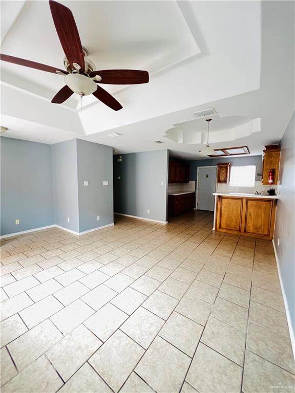 unfurnished living room featuring light tile patterned floors, a tray ceiling, and ceiling fan