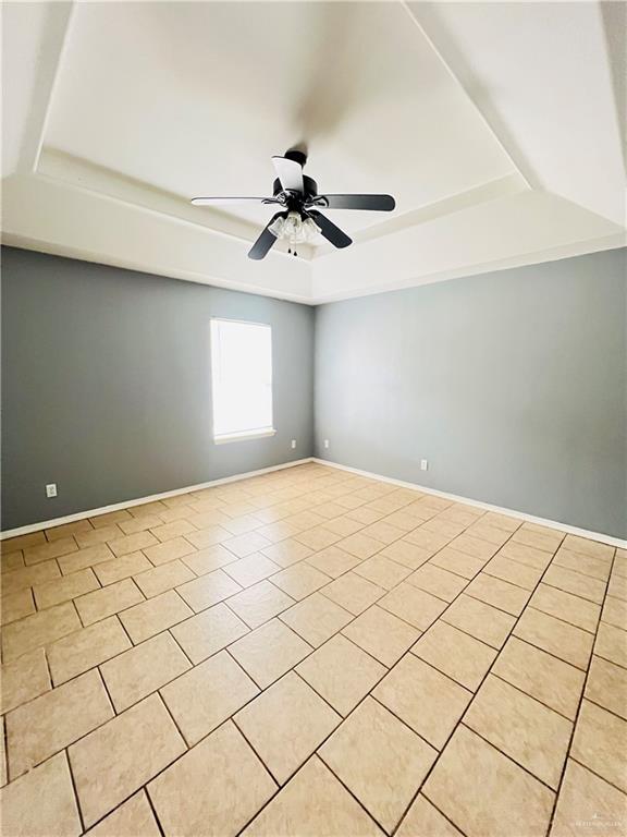 tiled spare room with a raised ceiling and ceiling fan