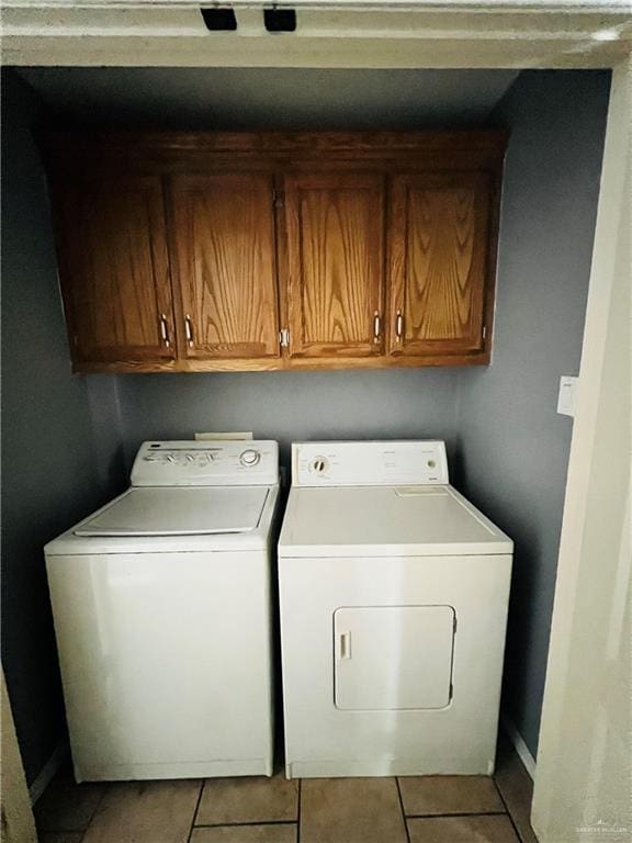 washroom with separate washer and dryer, light tile patterned flooring, and cabinets