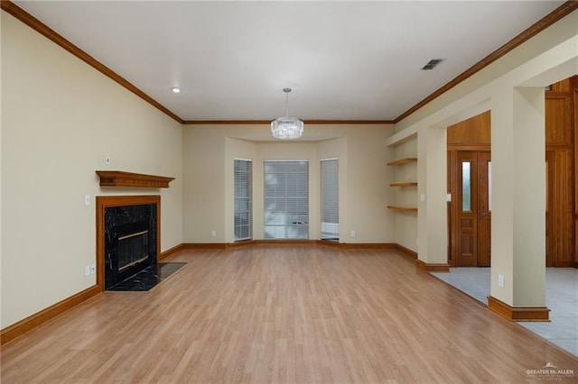 unfurnished living room featuring a chandelier, a fireplace, ornamental molding, and light wood-type flooring