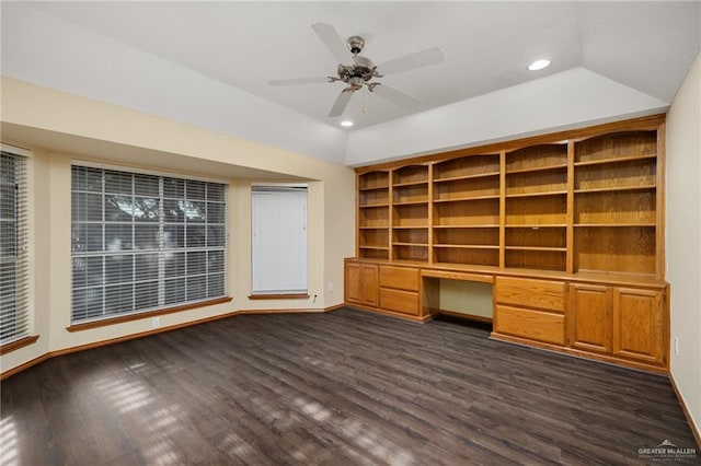 unfurnished office featuring ceiling fan, built in desk, and dark wood-type flooring