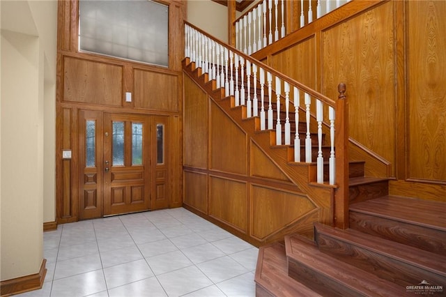 entryway with light tile patterned floors and a towering ceiling